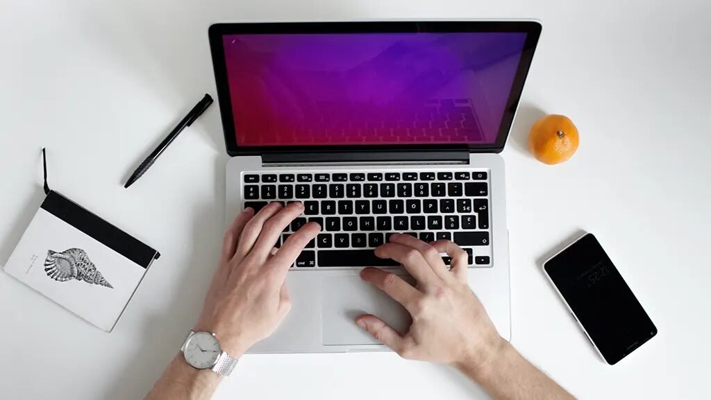 A person preparing to perform a factory reset on a silver MacBook Air laptop.